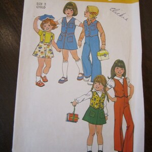 May include: A Simplicity sewing pattern for children's clothing. The pattern number is 7321 and the size is 2 child. The pattern shows four different outfits for girls, including a blue denim dress, a red and white gingham shirt with blue denim pants, a green skirt with a yellow and green vest, and a red pantsuit with a white shirt. The pattern is titled "Simplicity" and the price is $1.00.