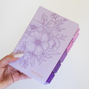 Custom engraved KJV Bible for women showcasing a soft purple leather binding, personalized name on the front cover, coordinating pink tabs, and traditional King James Version scripture, making a beautiful Christian keepsake gift for her faith journey