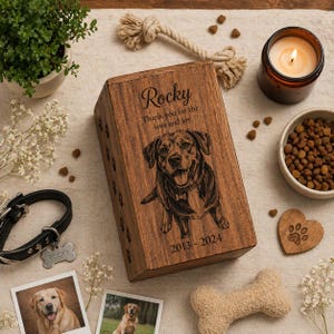 Puede incluir: Una caja conmemorativa rectangular de madera para mascotas con un retrato de perro grabado a l&aacute;ser, el nombre Rocky, el texto Thank you for the love and joy y los a&ntilde;os 2013-2024. La caja est&aacute; decorada con huellas de patas en el lateral.