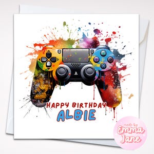 Op de afbeelding: Een wenskaart met een aquarel-achtige afbeelding van een gamecontroller. De controller is versierd met levendige spetters oranje, geel, blauw en rode verf. De woorden "HAPPY BIRTHDAY ALBIE" zijn in rood en blauw geschreven. Een roze ronde sticker met de woorden "made by Emma Jane" staat in de rechter benedenhoek.