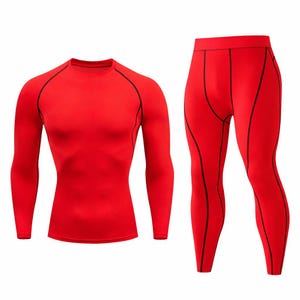 Puede incluir: Un conjunto de compresión rojo, que incluye una camiseta de manga larga y unos pantalones a juego. Ambas prendas tienen costuras negras. La camiseta tiene cuello redondo. La ropa deportiva está diseñada para el rendimiento y la comodidad.