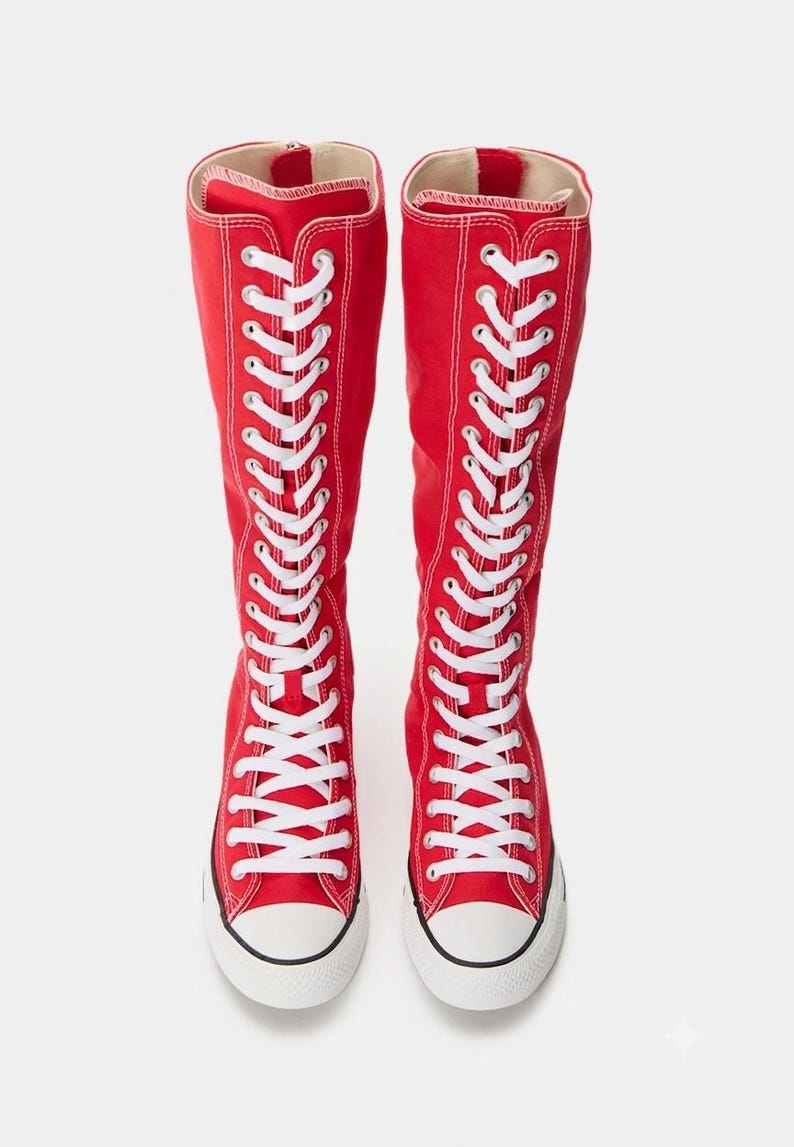 Puede incluir: Un par de botas altas de lona roja con cordones blancos que se extienden desde la punta hasta la parte superior de la ca&ntilde;a. Las botas tienen una puntera de goma blanca, una suela de goma blanca con una fina raya negra y una cremallera vertical en la parte posterior.