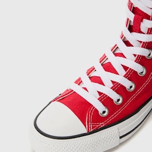 Puede incluir: Una zapatilla alta de lona roja brillante con cordones blancos, ojales met&aacute;licos plateados, puntera de goma blanca y suela de goma blanca con una fina raya negra a lo largo del borde de la construcci&oacute;n de la entresuela.