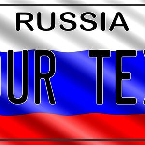 Puede incluir: Una placa de matrícula rectangular de metal con un diseño de bandera ondulada en blanco, azul y rojo. La palabra RUSSIA está impresa en negro en la parte superior central, y las palabras YOUR TEXT aparecen en letras mayúsculas negras.