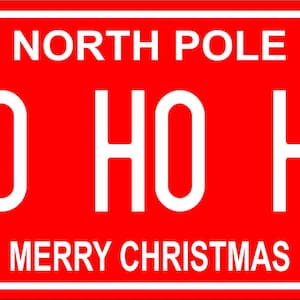 May include: A rectangular red license plate featuring white text. The top center reads NORTH POLE, with DEC on the left and 25 on the right. The center displays HO HO HO in large white letters, and the bottom reads MERRY CHRISTMAS in white text.