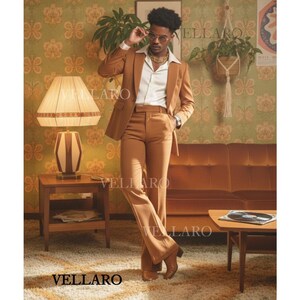 May include: A brown suit with a matching jacket and flared trousers. The suit is worn with a white collared shirt and gold chain. The image is set in a retro-style room with patterned wallpaper and a brown sofa. The word "VELLARO" is visible in the image.