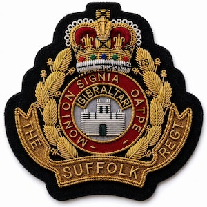 Puede incluir: Un parche bordado negro con una corona dorada sobre un emblema circular rojo con el texto MONION SIGNIA OATPE y GIBRALTAR. Un castillo plateado se sitúa en el centro, rodeado de hojas de laurel doradas y una cinta con THE SUFFOLK REGT.
