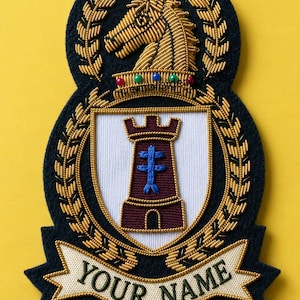 Op de afbeelding: Een donkerblauwe geborduurde patch met een gouden paardenkop boven een wit schild met een bordeauxrode kasteeltoren en een blauw kruis. Het ontwerp is omlijst door gouden laurierbladeren en bevat een witte banner met de tekst YOUR NAME.