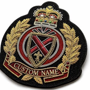 Peut inclure: Un écusson brodé noir orné d'une couronne dorée, de feuilles de laurier et d'un écusson rouge et or. Le patch porte l'inscription "CUSTOM NAME" en lettres dorées sur une bannière rouge. Le design est complexe.