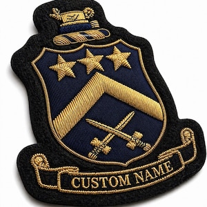 Puede incluir: Parche bordado con un diseño de escudo. El parche presenta un escudo azul marino con estrellas, galones y espadas cruzadas de color dorado. El texto "CUSTOM NAME" está bordado en una pancarta dorada. El parche está contorneado en negro.