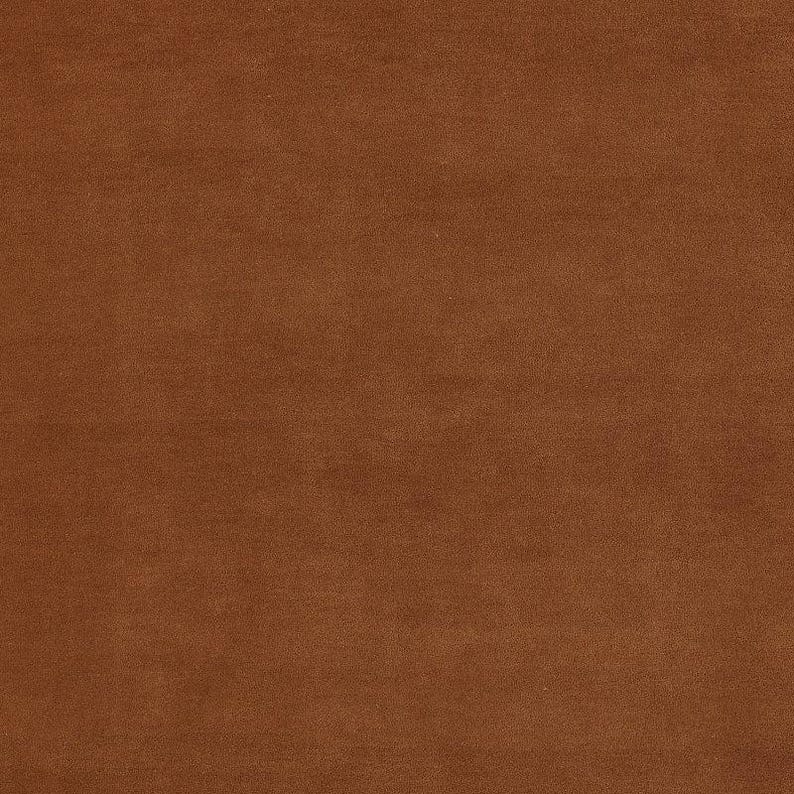 May include: A close-up shot of a solid, textured fabric in a warm, earthy brown color. The material appears to be soft, possibly velvet or suede, with a subtle sheen. The fabric is evenly lit, showing its smooth surface.