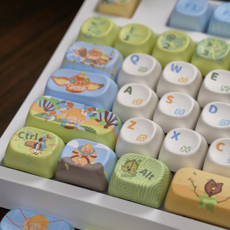 Puede incluir: Primer plano de un teclado personalizado con teclas coloridas. Las teclas presentan varias ilustraciones y texto, incluyendo "Ctrl" y "Alt". Las teclas son una mezcla de blanco, azul, verde y amarillo, con dise&ntilde;os de estilo caricatura.