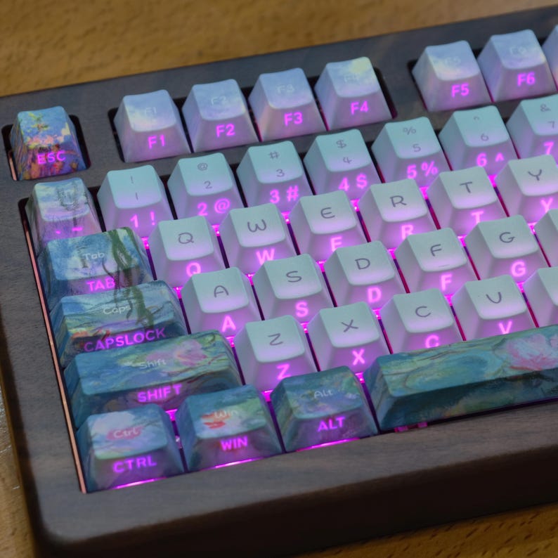 May include: A mechanical keyboard with a dark wood frame and white keys featuring pink backlighting. The left-side keys, including Esc, Tab, Caps Lock, Shift, Ctrl, Win, and Alt, feature a blue and pink floral art print. The standard keys display white letters.