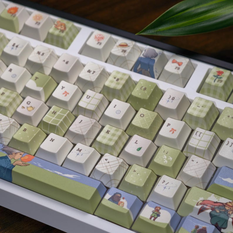 May include: A custom mechanical keyboard with white and green keycaps. The keycaps feature various designs, including floral patterns, geometric shapes, and illustrations. The keyboard has a white frame and a dark wooden surface in the background.