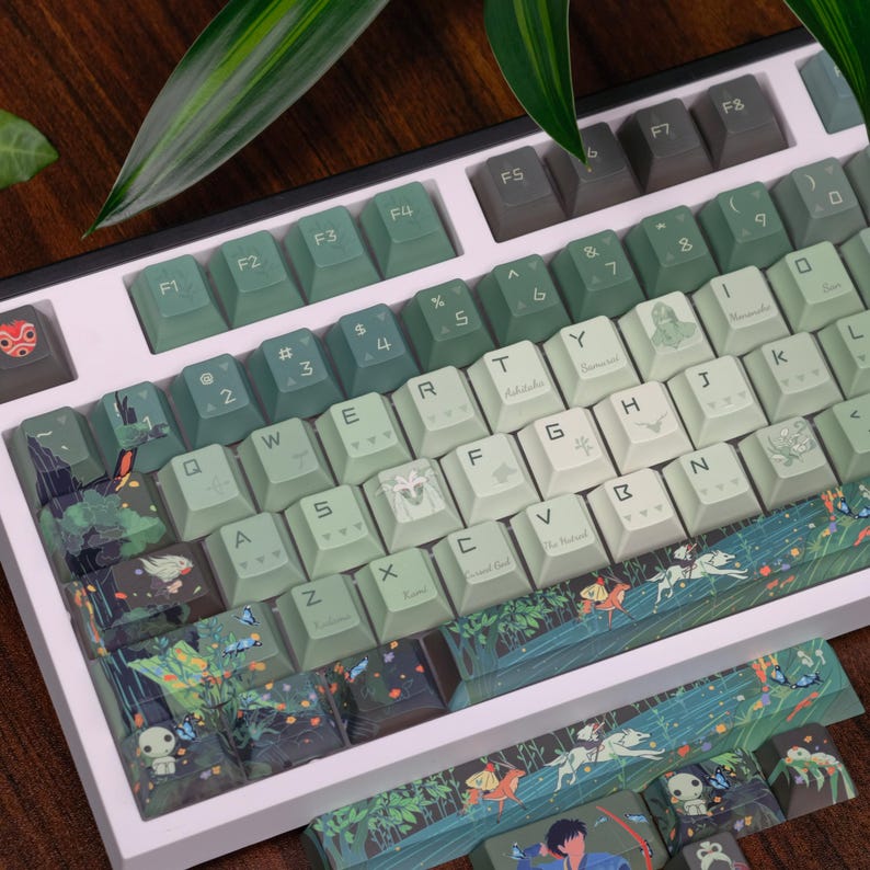 May include: A custom mechanical keyboard with keycaps in shades of green and white, featuring nature-themed artwork and illustrations. The keyboard has a white frame and a variety of keycap designs, including forest scenes and character art.