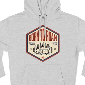 May include: A light gray hooded sweatshirt with a front pocket. The sweatshirt features a graphic on the front that says "BORN TO ROAM" inside a red and beige hexagon. The graphic includes a camper van, trees, and a campfire.