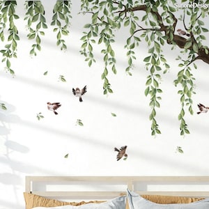 Può includere: Un adesivo murale con un'illustrazione ad acquerello di un albero con foglie verdi e diversi piccoli uccelli in volo. I rami dell'albero si estendono sulla parte superiore, con foglie a cascata. Gli uccelli sono marroni e bianchi, con tema natura e decorazione.
