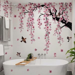 May include: A white bathroom with a large oval bathtub. The walls are decorated with a cherry blossom tree design in pink and black, with small birds. The text "Sunone Designs" is in the upper left corner.