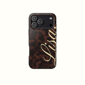 Op de afbeelding: Een bruin en zwart telefoonhoesje met een schildpadpatroon. De hoes heeft de naam "Lisa" in een gouden scriptlettertype. De telefoon heeft drie cameralenzen en een flitser.