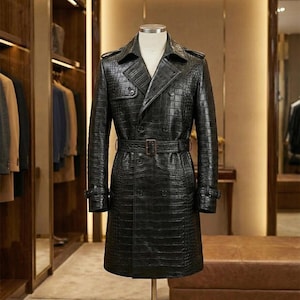 Könnte beinhalten: Ein schwarzer Trenchcoat mit Krokodilmuster, doppelreihigem Design und Gürtel. Der Mantel hat einen Reverskragen und geknöpfte Manschetten. Er wird auf einer Schaufensterpuppe in einem Raum mit Holzschrank präsentiert.
