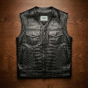Peut inclure: Gilet en cuir noir avec une texture peau de crocodile. Le gilet a un col en V, deux poches de poitrine et deux poches latérales. La marque "CROCY" est visible à l'intérieur.