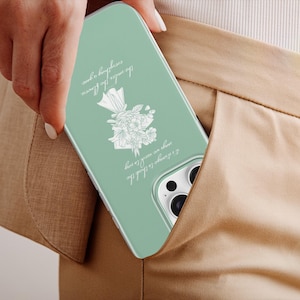 May include: A mint green phone case with a floral design and script. The case is in a pocket of tan pants. The script reads: "I always like to think the flowers are awake at night, everything a dream."