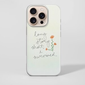 May include: A phone case with a clear border and a soft gradient background. The case features the handwritten text "long story short, I survived" with a small floral illustration in orange and green.