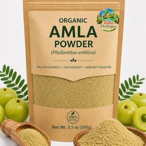 May include: A brown paper bag of organic Amla powder, with the text "AMLA POWDER" and "(Phyllanthus emblica)". A wooden bowl and scoop hold the powder, with green Amla fruits in the background. The bag contains 100g of powder.