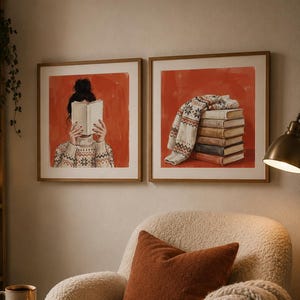May include: Two square framed art prints hanging on a wall. The left print shows a person with a dark bun hairstyle wearing a patterned sweater while reading a book. The right print depicts a stack of books topped with a folded patterned sweater.