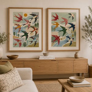 Puede incluir: Dos cuadros de pared con ilustraciones estilizadas de pájaros coloridos en vuelo sobre un paisaje con árboles, colinas y un sol amarillo. Las láminas están enmarcadas en madera clara y colgadas una al lado de la otra en una pared neutra.