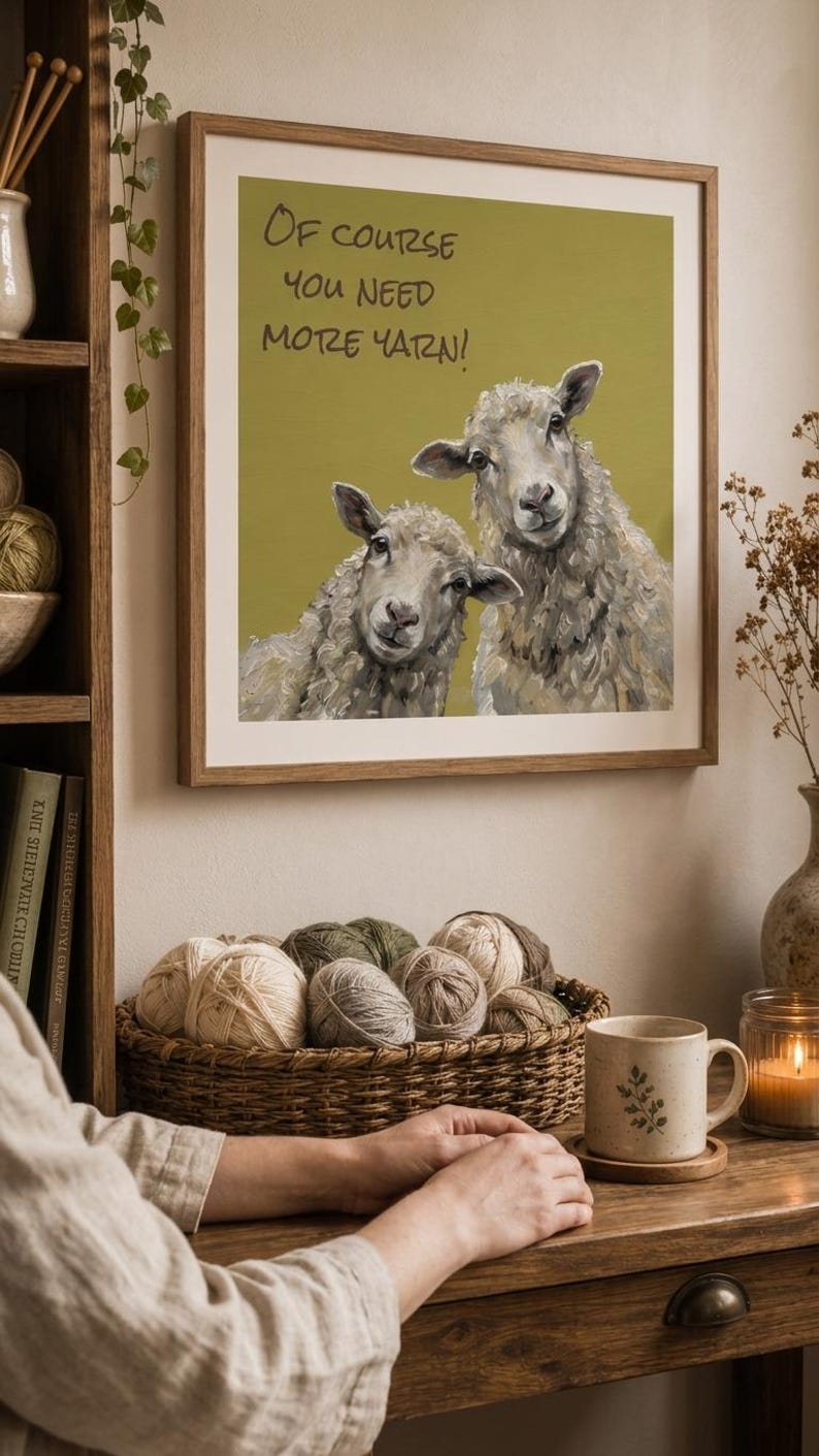 May include: A square framed wall art print featuring an olive green background with two sheep and the text "Of course you need more yarn!" in black lettering. The artwork is displayed in a light wood frame, showcasing a detailed painting of sheep.