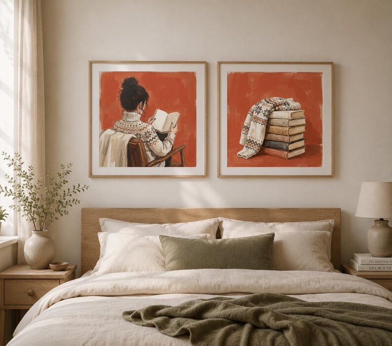 May include: Two square framed wall art prints featuring a burnt orange background. The left print shows a person in a cream-coloured patterned jumper reading a book. The right print displays a stack of books topped with a folded patterned jumper.