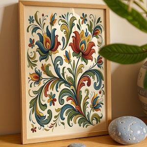 May include: A framed floral print with a light wood frame. The artwork features a symmetrical design of stylized flowers and leaves in shades of red, blue, yellow, and green against a cream background. The print is leaning against a wall.