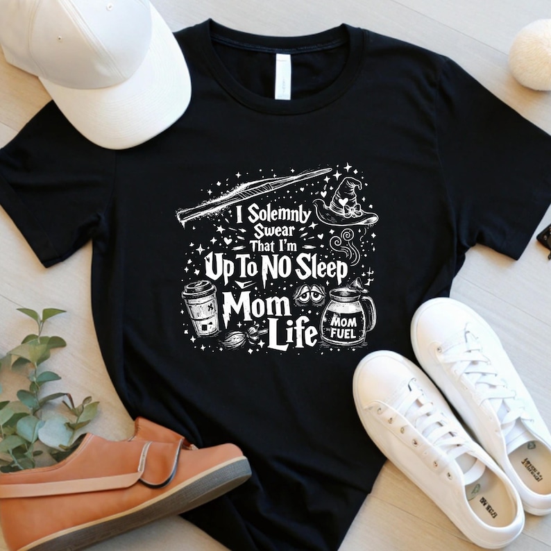 May include: A white ceramic mug with a black handle and the text "But First, Coffee" in a black, handwritten-style font. The mug is on a white surface.