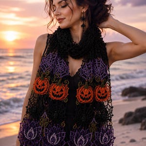 May include: A black crocheted scarf with Halloween-themed embellishments. The scarf features orange jack-o'-lanterns, purple spiderwebs, and purple floral designs. The scarf is worn over a black dress, with a beach and sunset in the background.