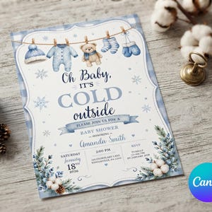 May include: A baby shower invitation card featuring a blue plaid border, snowflakes, and a clothesline with a hat, onesie, teddy bear, socks, and mittens. The text reads: Oh Baby, IT'S COLD outside, PLEASE JOIN US FOR A BABY SHOWER, Amanda Smith, January 18th, 2026.