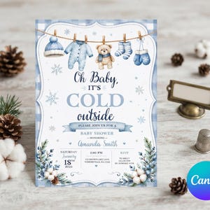 May include: A baby shower invitation card featuring a blue and white buffalo check border, a clothesline with a hat, onesie, teddy bear, socks, and mittens, and the text Oh Baby, IT'S COLD outside, Amanda Smith, January 18th, 2020, 2:00 PM.