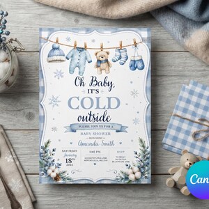 May include: A rectangular baby shower invitation card featuring a blue and white gingham border, a clothesline with winter baby clothes, and a teddy bear. The text reads: Oh Baby, IT'S COLD outside, PLEASE, JOIN US FOR A BABY SHOWER, HONORING, Amanda Smith.