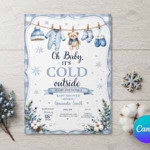 May include: A baby shower invitation card featuring a blue plaid border and a clothesline with a winter hat, onesie, teddy bear, socks, and mittens. The text reads Oh Baby, IT'S COLD outside, honoring Amanda Smith, Saturday January 18th 2024.
