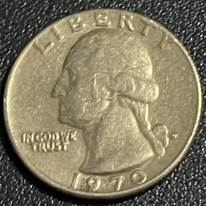 May include: A silver 1970 quarter coin. The coin features a profile of George Washington, the word "LIBERTY" at the top, and "IN GOD WE TRUST" below. The year "1970" is at the bottom.