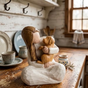 Könnte beinhalten: Eine Holzfigur, die eine Person zeigt, die einen kleinen braunen Hund umarmt. Die Figur trägt ein weißes Gewand und hat lange braune Haare. Die Figur steht auf einer Holzoberfläche.