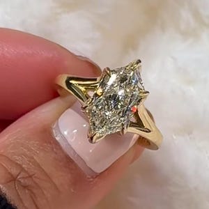 May include: A gold ring featuring a marquise-cut diamond set in a prong setting with a split shank band. The text "This is what you call..." is displayed at the top of the image. The ring has a polished yellow gold finish and a clear faceted stone.