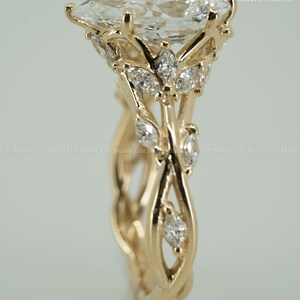May include: A gold engagement ring with a large, pear-shaped diamond as the centerpiece. The ring features a floral design with smaller diamonds and intricate detailing on the band. The ring is set against a soft, neutral background.