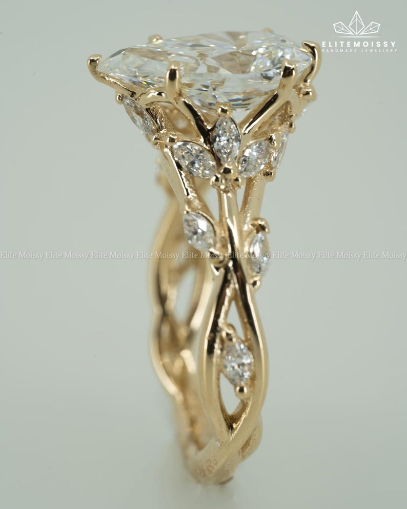 May include: A gold engagement ring with a large, pear-shaped diamond as the centerpiece. The ring features a floral design with smaller diamonds and intricate detailing on the band. The ring is set against a soft, neutral background.