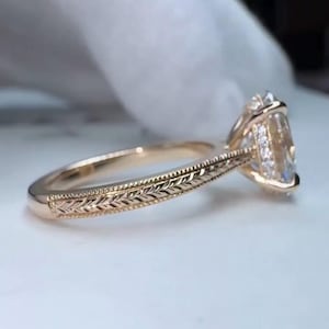 Op de afbeelding: Een roségouden verlovingsring met een peervormige diamant. De band heeft een gegraveerd bladerenpatroon. Kleine diamanten zijn rond de hoofdsteen gezet.