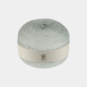 May include: A ball of light blue yarn with a cream-colored label wrapped around the center. The label features a logo and the word "YARN". The yarn appears to be tightly wound and ready for crafting projects.