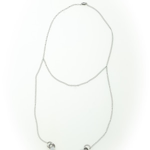 May include: A silver-toned body chain necklace. The necklace features a delicate chain that drapes across the chest and connects to two small, circular charms. The design is simple and elegant, suitable for layering or wearing alone.