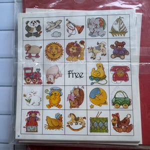May include: A white bingo card featuring a five-by-five grid of colorful cartoon illustrations, including a panda, airplane, trumpet, elephant, sailboat, sheep, sun, lion, cow, teddy bear, train, pig, duck, telephone, rabbit, cat, moon, car, jester, chicken, rocking horse, drum, and dog, with the word Free in the center.
