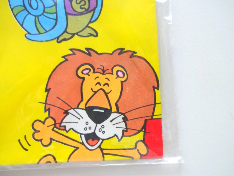 May include: A cartoon lion with a bright orange mane and a big smile. The lion is wearing a red shirt and has a yellow background.