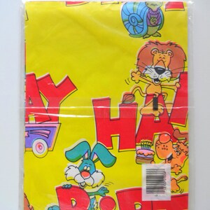 May include: Yellow wrapping paper with a colorful cartoon design. The paper features the words "Happy Birthday" in large red letters and various animals including a lion, a rabbit, and a snail.